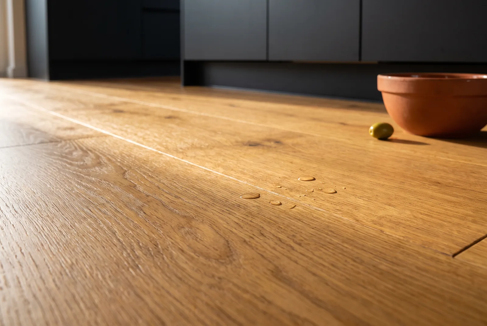 Gouttes d'eau perlant sur un parquet chêne huilé en cuisine