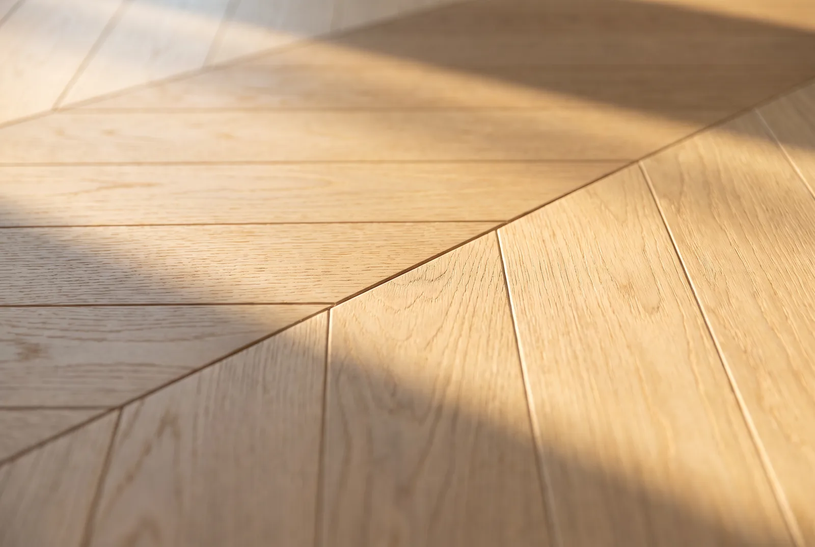 Détail d'un parquet chevron en chêne clair sous lumière rasante